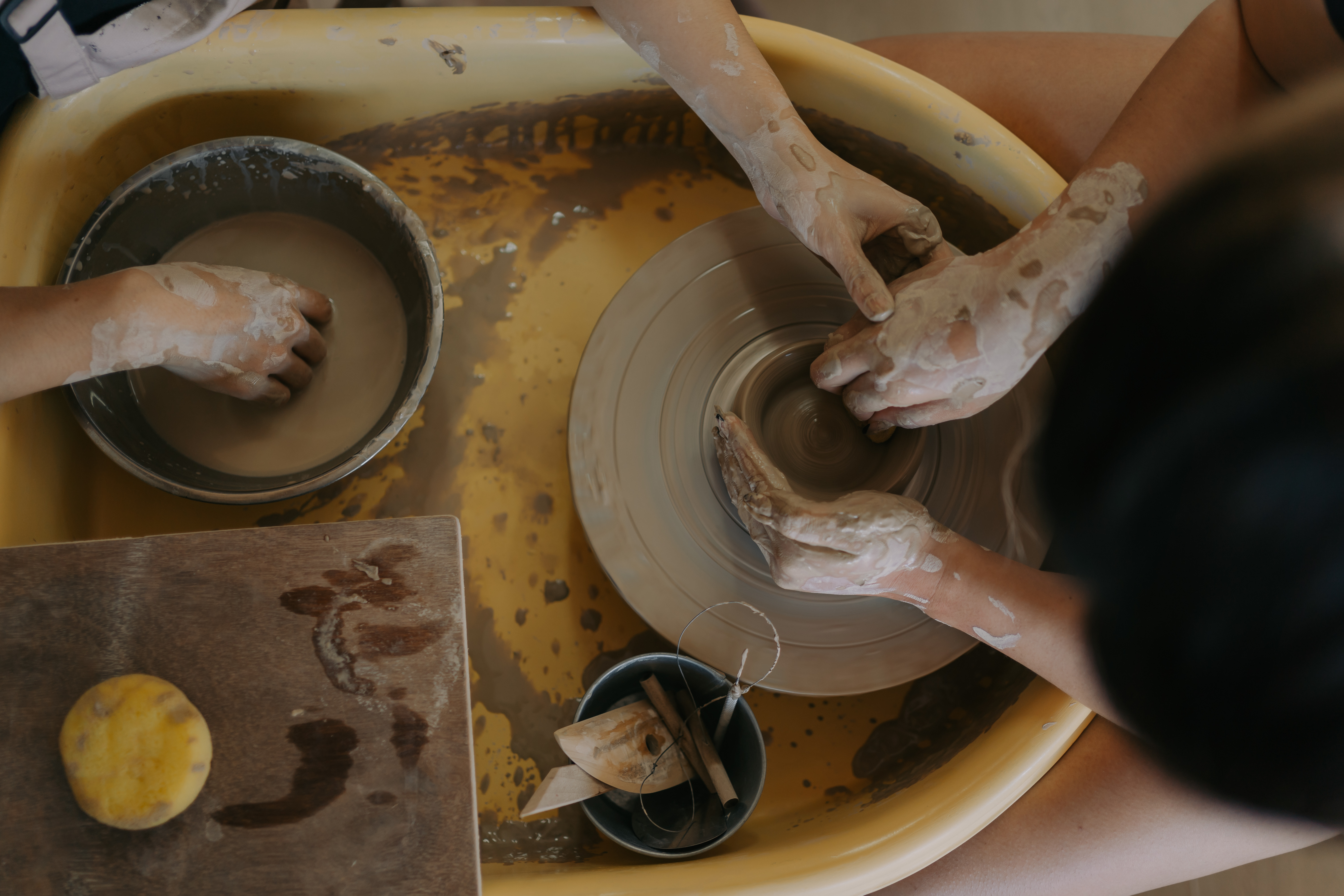Hands shaping clay on the pottery wheel
