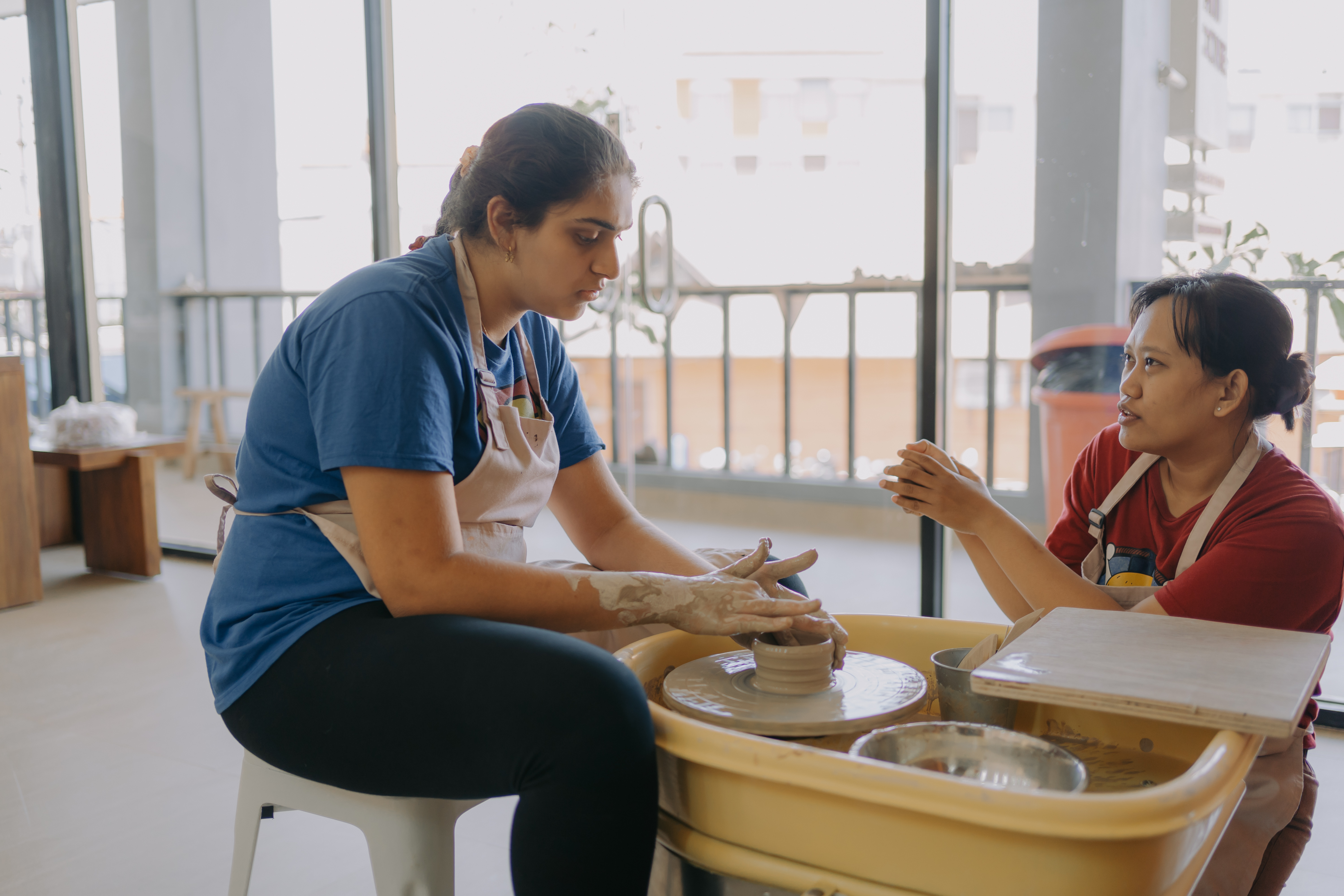 Instructor guiding a guest on the pottery wheel